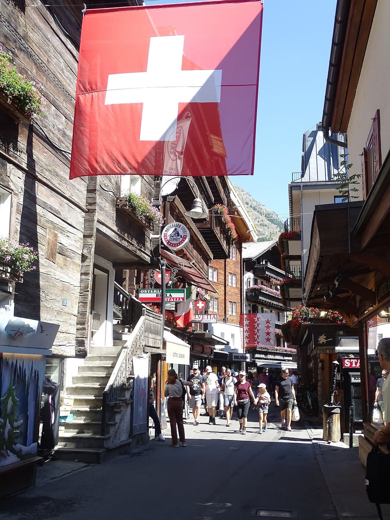 Bahnhofstrasse in Zermatt, a pedestrian street under a Swiss flag